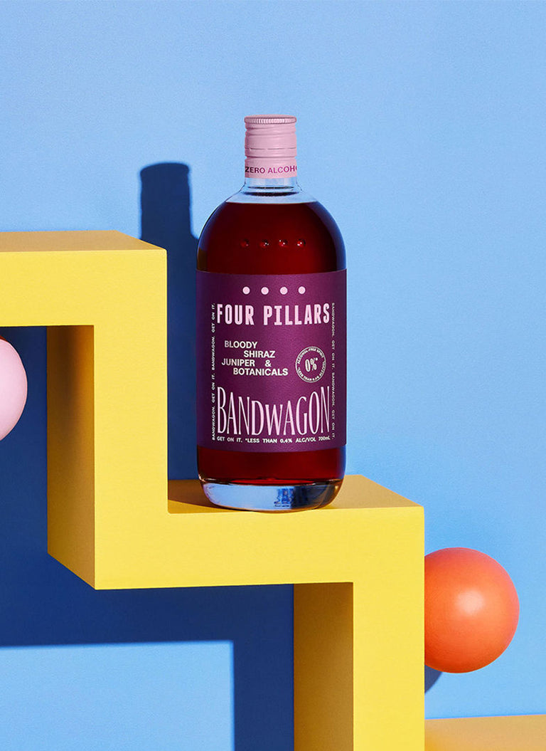 A deep etch image of a bottle of Four Pillars Gin Bloody Bandwagon, a non-alcoholic gin on a yellow shelf with a blue background